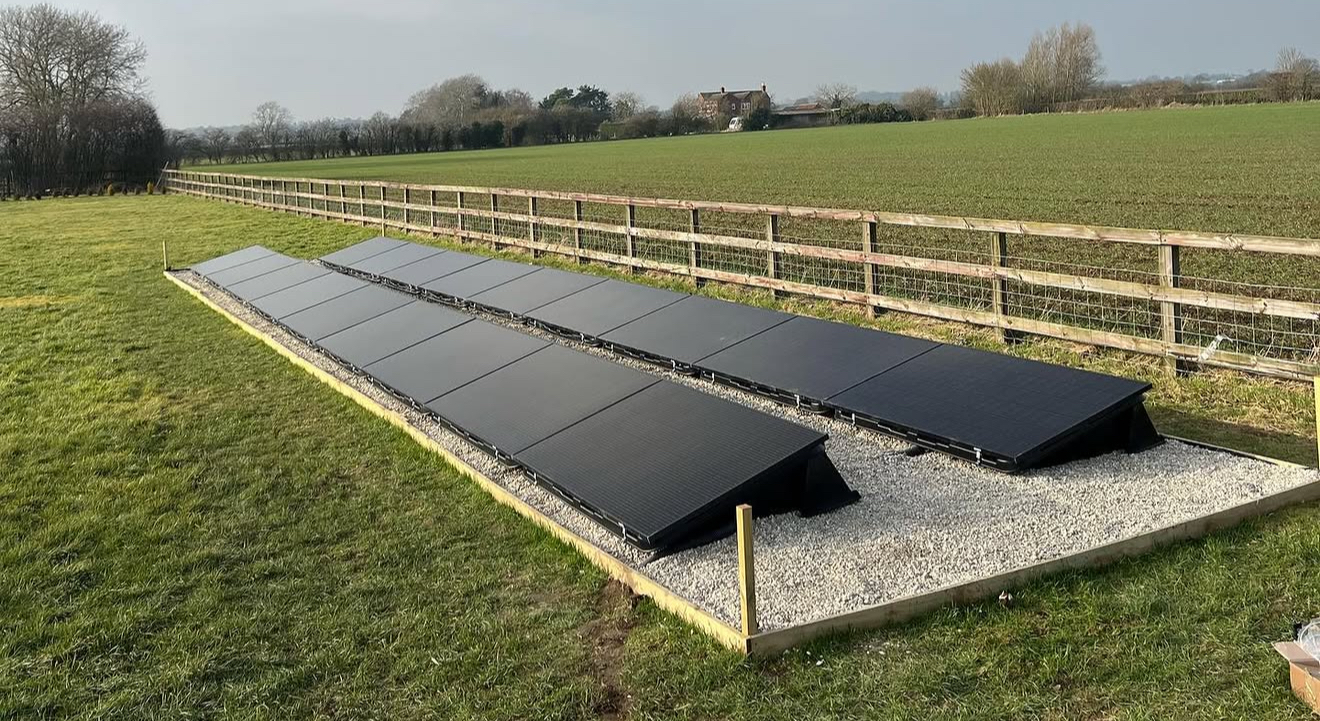 Ground-mounted solar array on a gravel base beside a field