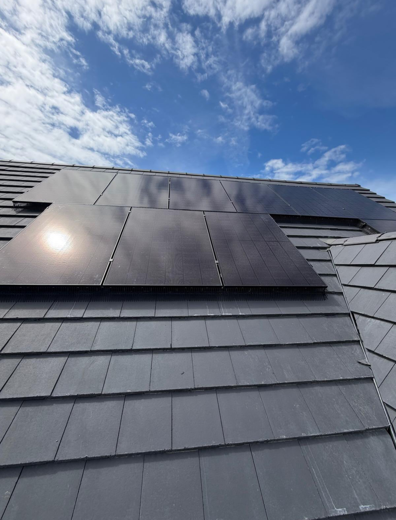 Solar panels on a slate roof under a blue sky