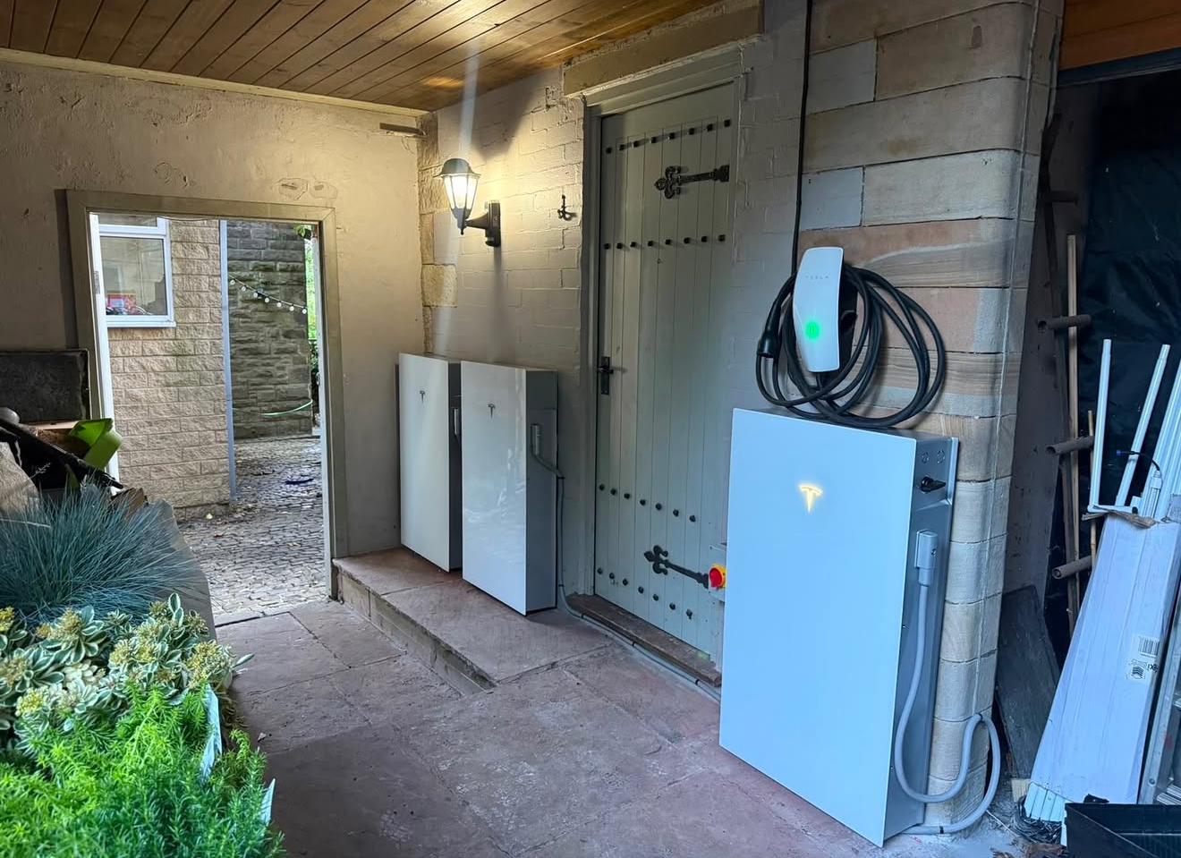 Tesla wall connector installed beside a Tesla Powerwall battery
