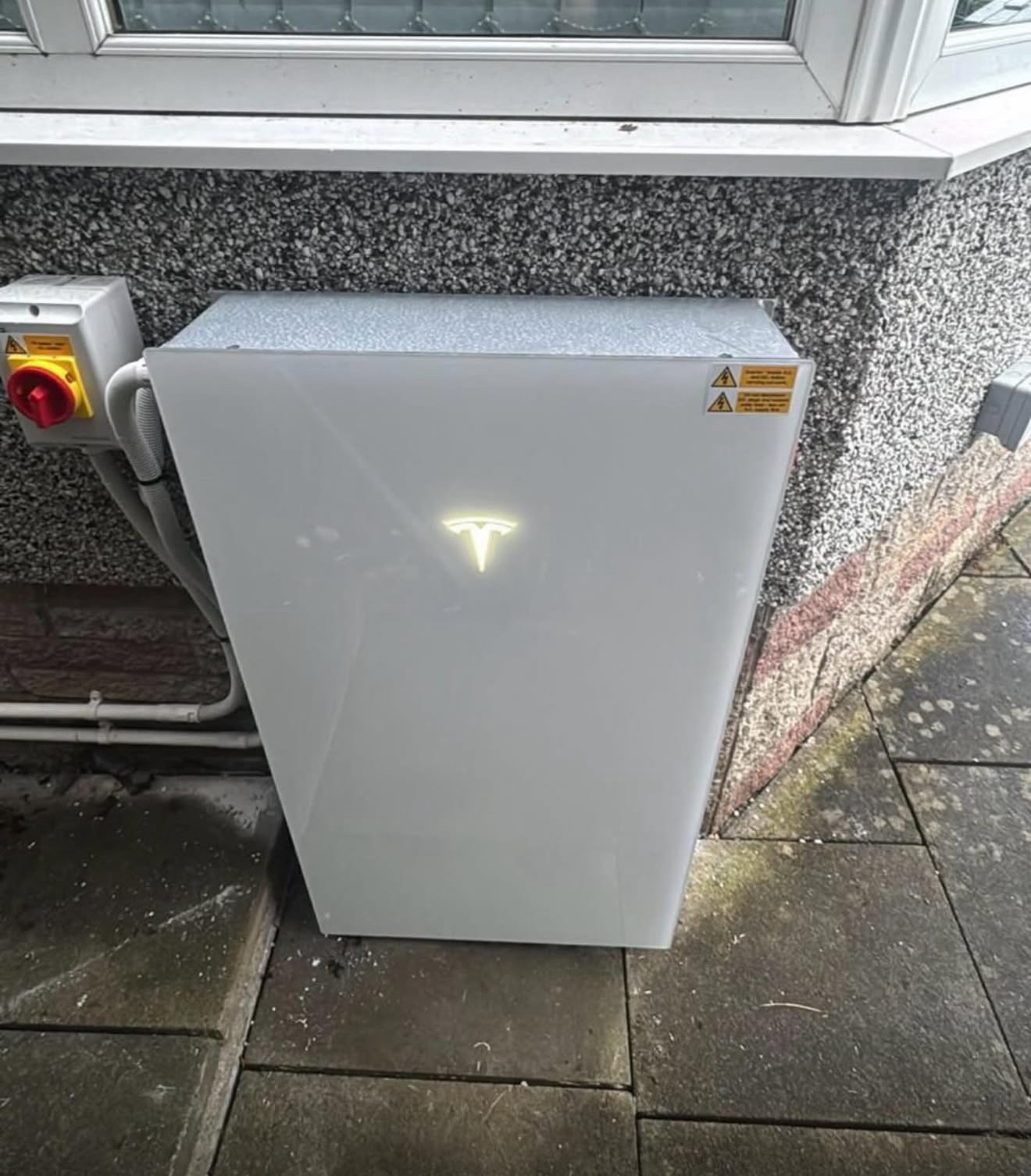 White home battery installed against an external house wall